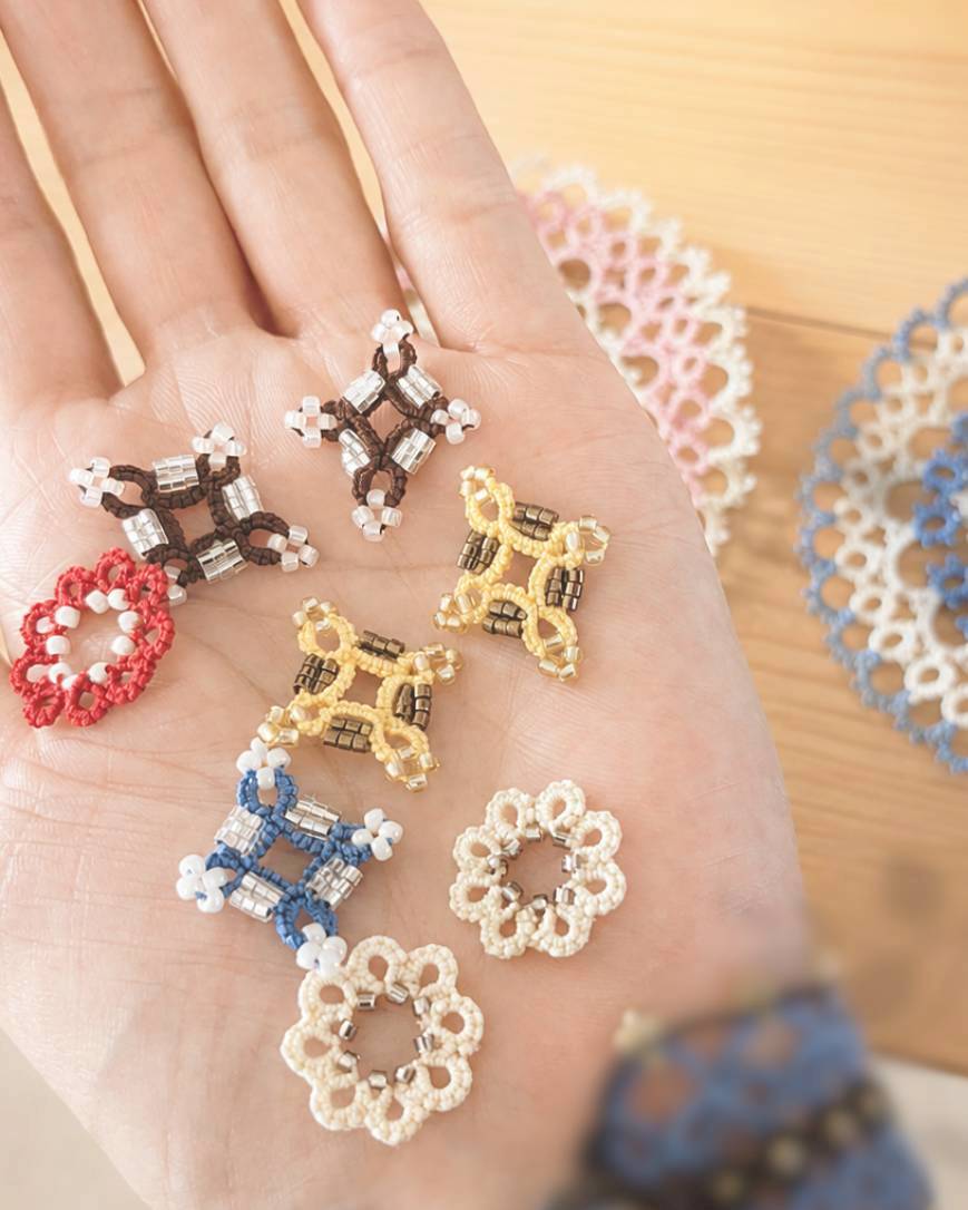 手のひらに並べた色とりどりの小さなレース作品